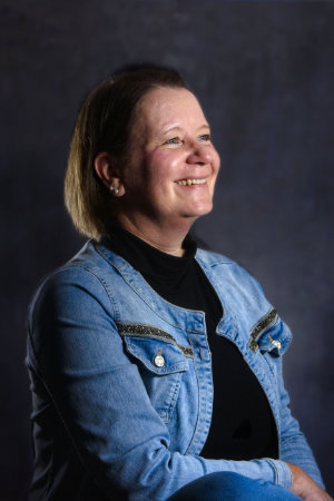 Business Portrait einer Frau vor dunklem Hintergrund.