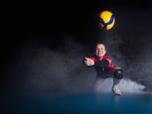 Volleyball Spielerin baggert einen Ball, im Hintergrund ist Nebel zu sehen.